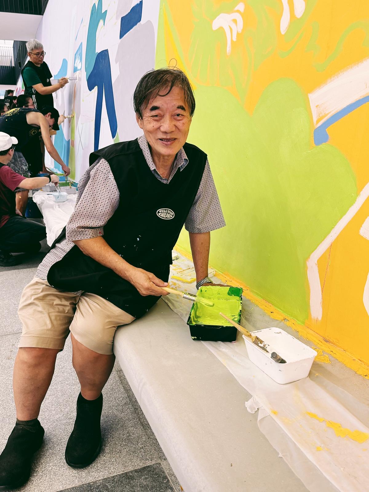 Behind the scenes photo of community members posing by the mural