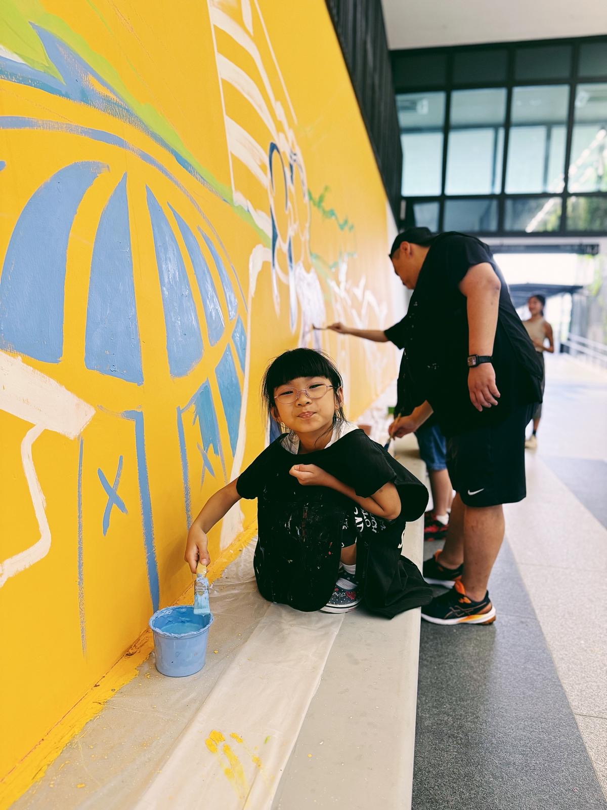 Behind the scenes photo highlighting community members painting together